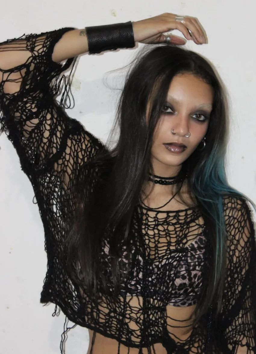 K⭐Y in a black mesh top, one hand raised to her head